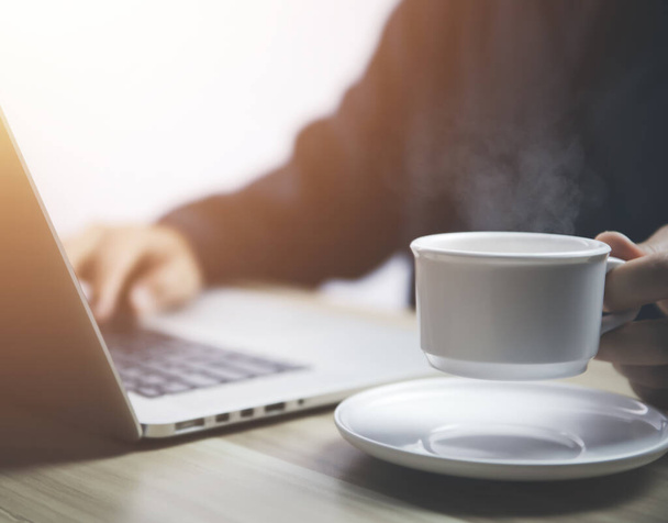 Podnikatel pracující před laptopem s šálkem horké kávy, která má kouř a páru - Fotografie, Obrázek
