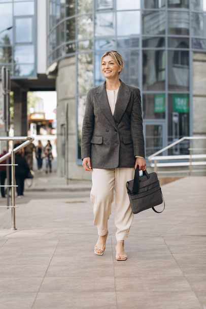 Porträt einer reifen Geschäftsfrau mit emotionalem Lächeln auf modernem Büro und urbanem Hintergrund - Foto, Bild
