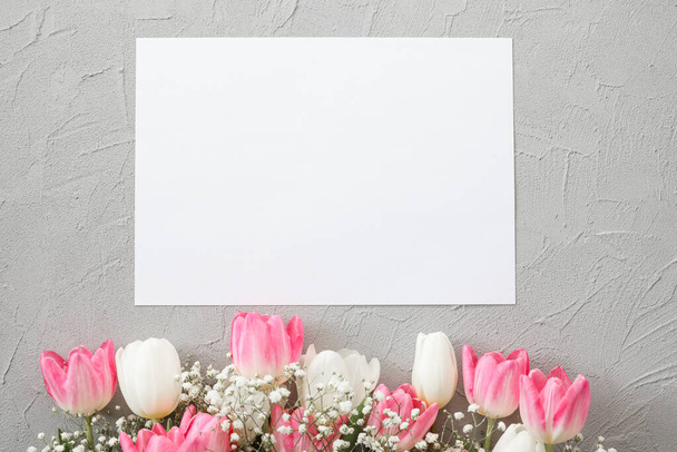 Pink tulips and white gypsophila flowers bouquet on a stylish gray stone background. Mothers Day, birthday celebration concept. Copy space for text. Mockup - Fotografie, Obrázek