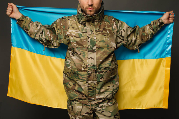 Portrait of a courageous Ukrainian military man holding the flag of Ukraine, freedom concept - Fotó, kép