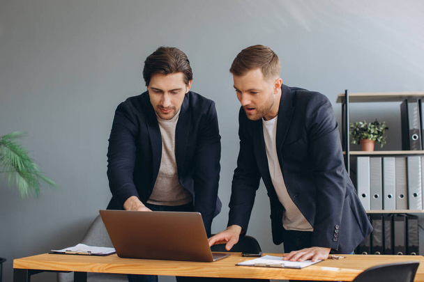 Liiketoimintatiimityöskentely - kaksi liikemiestä työskentelee yhdessä kannettavan tietokoneen parissa - Valokuva, kuva