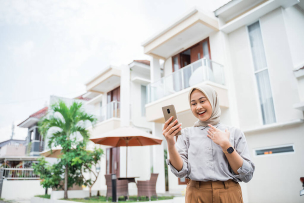 attractive woman in hijab using cell phone in residential background - Foto, imagen