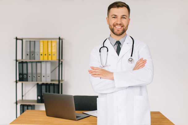Portrait of happy doctor with stethoscope at workplace in clinic - Photo, Image