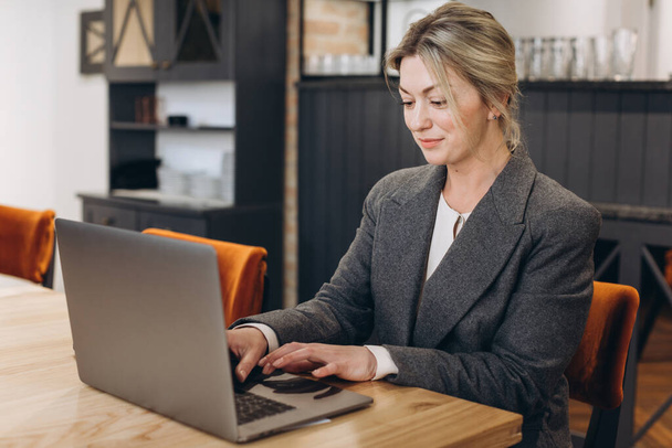 Зріла ділова жінка адміністратор ресторану сидить і працює на ноутбуці
 - Фото, зображення