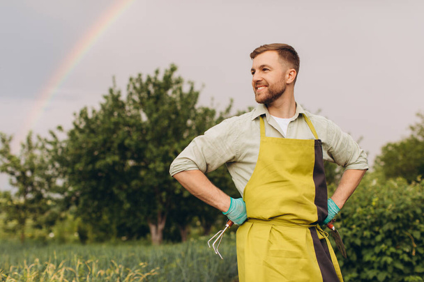 Retrato de un granjero sonriendo sobre un fondo de arco iris en el jardín - Foto, Imagen