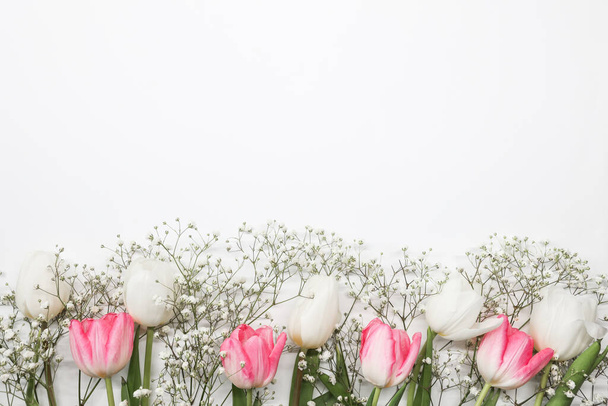 Rosafarbene Tulpen und weiße Zigeunerblumen blühen auf weißem Hintergrund. Muttertag, Geburtstagsfeier. Kopierraum für Text - Foto, Bild