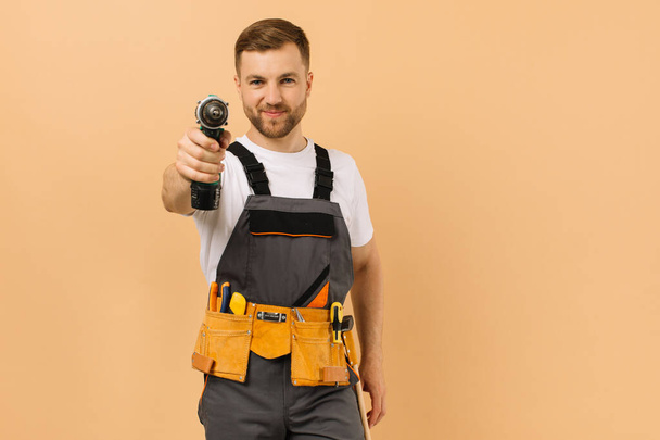 Reparador masculino positivo en casa con destornillador sobre fondo beige - Foto, imagen