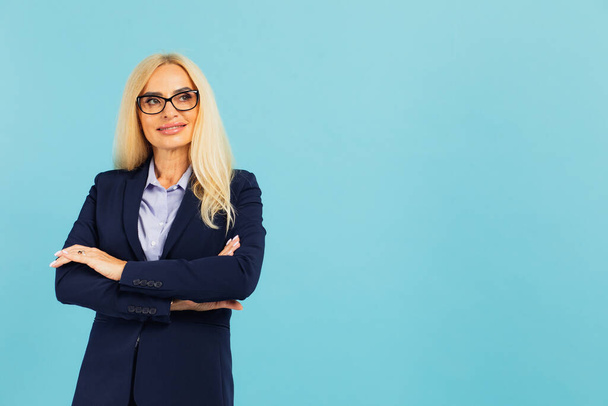 Portret van een aantrekkelijke zakenvrouw van middelbare leeftijd op een blauwe achtergrond - Foto, afbeelding