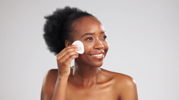 Skincare, cotton pad and black woman isolated on studio background for face or facial cleaning product promotion. Young model or person with beauty glow, cosmetics wipe and makeup in studio mockup. - Video