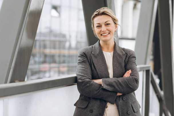 Πορτρέτο μιας ώριμης γυναίκας επιχειρηματία χαμογελώντας με τα συναισθήματα στο σύγχρονο γραφείο και αστικό υπόβαθρο - Φωτογραφία, εικόνα