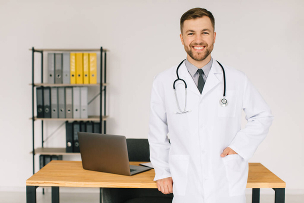 Портрет щасливого лікаря зі стетоскопом на робочому місці в клініці
 - Фото, зображення