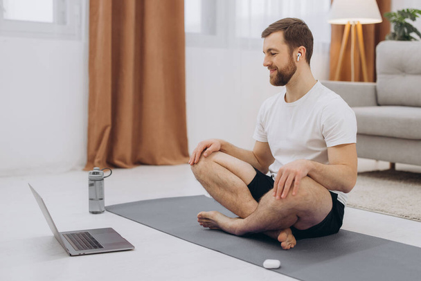 Uklidněte se v karanténě. Millennial chlap meditace s trenérem on-line přes notebook připojení, prázdné místo - Fotografie, Obrázek