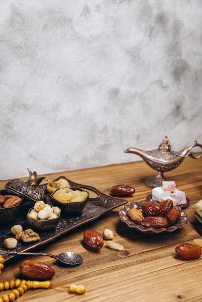 Dried dates and tea on a wooden table. Arabic traditional dishes, pots and dates fruits. Ramadan Kareem, Eid mubarak concept. Copy space - Photo, image
