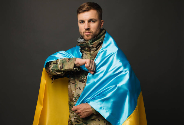 Portrait of a courageous Ukrainian military man holding the flag of Ukraine, freedom concept - Photo, image