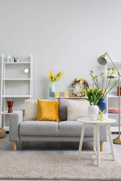 Interior of living room with Easter wreath, decor and sofa - Photo, image