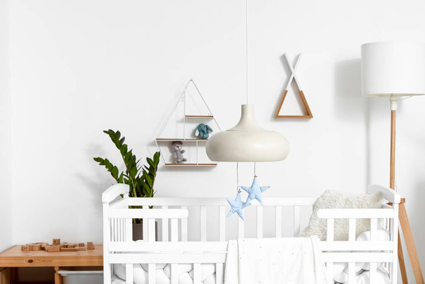 Interior of light children's bedroom with baby crib and shelves - Photo, Image