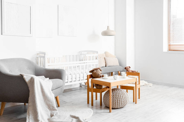 Interior of light children's bedroom with baby crib, table and chairs - Fotografie, Obrázek