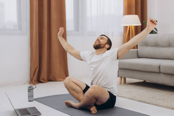 Blijf kalm in quarantaine. Millennial guy mediteren met trainer online via laptop verbinding, lege ruimte - Foto, afbeelding