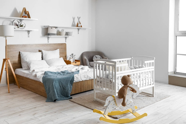 Interior of light bedroom with bed, baby crib and toys - Photo, Image