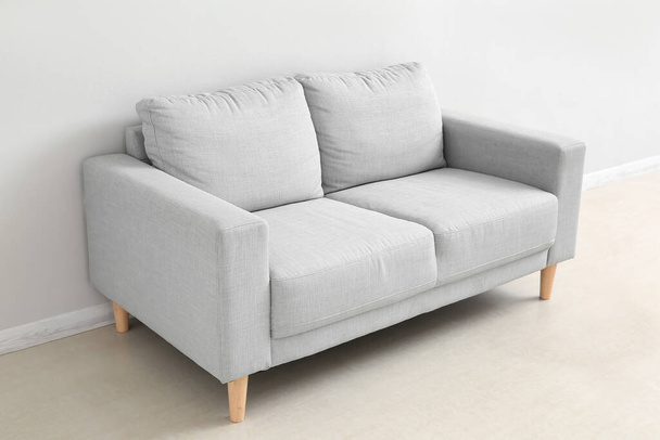 Stylish grey sofa near white wall - Fotó, kép
