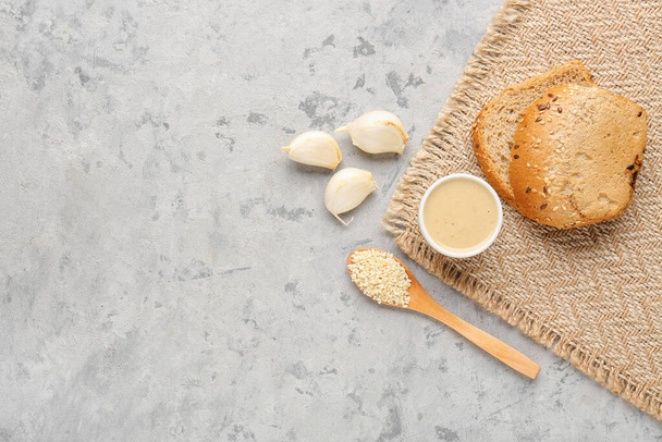 Чаша вкусного тахини, кунжута, чеснока и хлеба на фоне гранжа - Фото, изображение