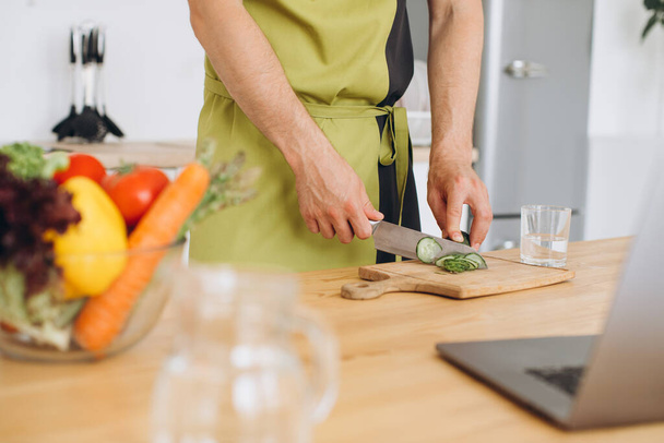Fragment muže, který dělá salát z čerstvé zeleniny v kuchyni doma. - Fotografie, Obrázek