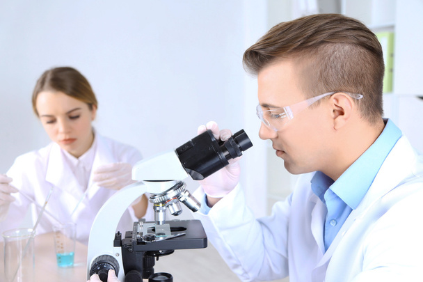 Giovani scienziati di sesso femminile e maschile con microscopio in laboratorio
 - Foto, immagini