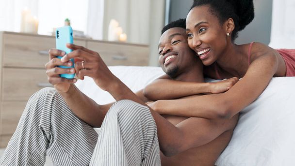 Πορτρέτο, τηλέφωνο και ζευγάρι βγάζουν μια selfie στο υπνοδωμάτιο μαζί και την μοιράζονται σε εφαρμογή κοινωνικής δικτύωσης online το πρωί. Μέσα κοινωνικής δικτύωσης, χαμόγελο και μαύρη γυναίκα αγαπά τη λήψη φωτογραφιών με αφρικανικό εταίρο. - Φωτογραφία, εικόνα