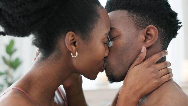 Couple kiss, bedroom sex and love on bed in house, erotic sexual energy in marriage and nude people being sexual together in home. Happy African man and woman kissing with passion in apartment. - Фото, изображение