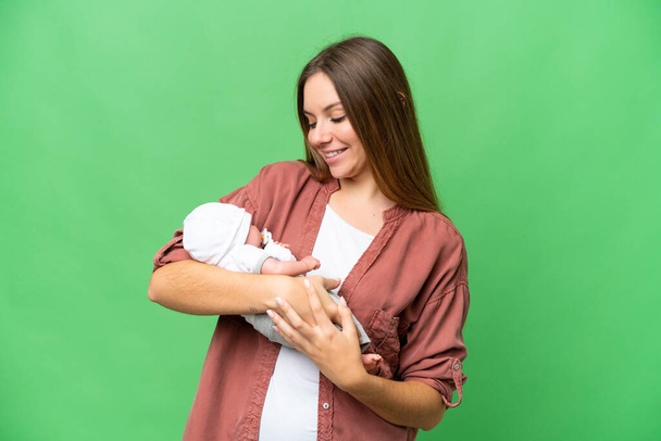 Young blonde woman  with her newborn baby over isolated chroma key background with happy expression - Fotó, kép