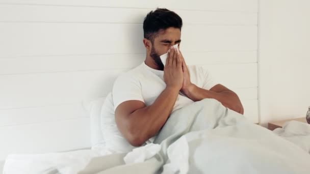 Sick, covid and bed with a man sneezing or blowing his nose in the bedroom of his home while on leave. Health, cold and ill with a handsome young male suffering from a virus infection in his house. - Footage, Video