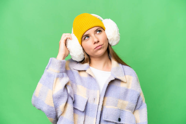 Jeune femme blonde portant des manchons d'hiver sur fond isolé chroma clé ayant des doutes et avec une expression du visage confus - Photo, image