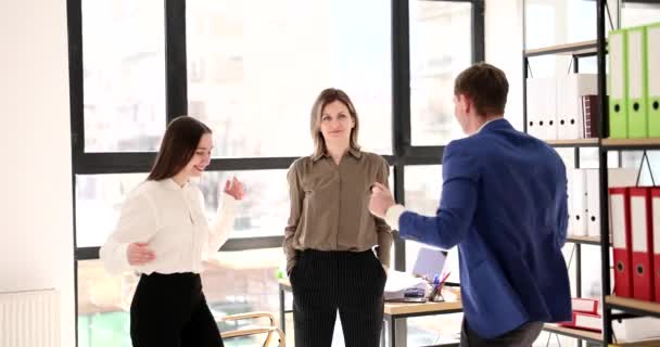 Vrouw kijkt verbaasd naar vrolijke succesvolle collega 's en begint met hen te dansen. Teamwork en succesvol business team - Video