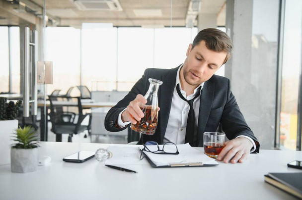 Businessman drinking from stress at workplace. - 写真・画像