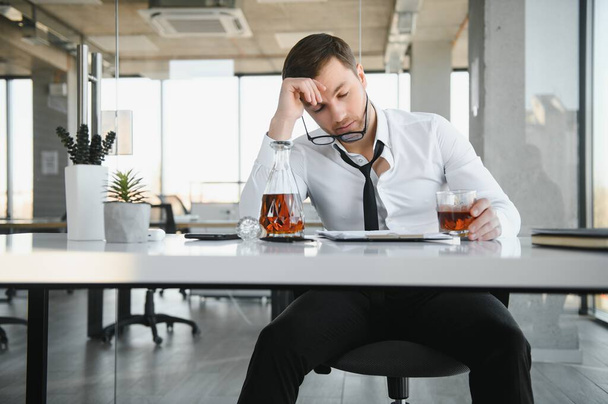 Businessman drinking from stress at workplace. - Foto, afbeelding