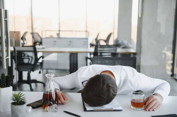 Alcoholism at work. Tired employee drinking alcohol at workplace, can not handle stress - Foto, Imagem