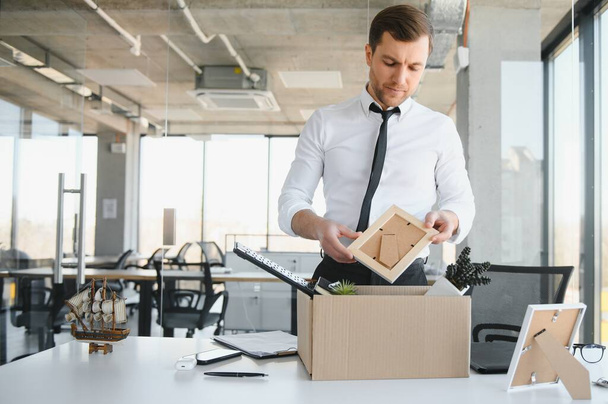 Sad Fired. Let Go Office Worker Packs His Belongings into Cardboard Box and Leaves Office. Workforce Reduction, Downsizing, Reorganization, Restructuring, Outsourcing. Mass Unemployment Market Crisis. - Fotoğraf, Görsel