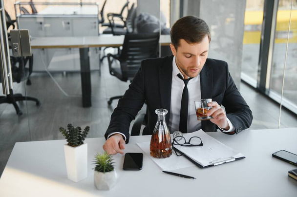 Young businessman drinking from stress. - Foto, Bild