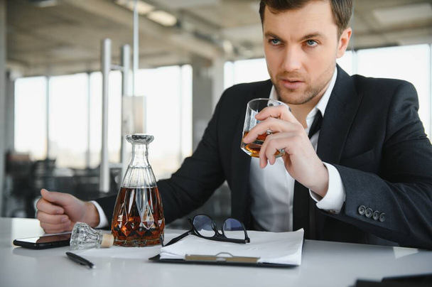 Young businessman drinking from stress. - Фото, изображение