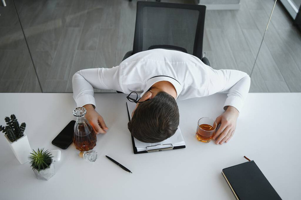 Alcoholism at work. Tired employee drinking alcohol at workplace, can not handle stress - Фото, зображення