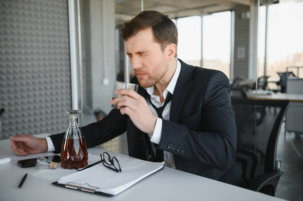Businessman drinking from stress at workplace. - Фото, зображення