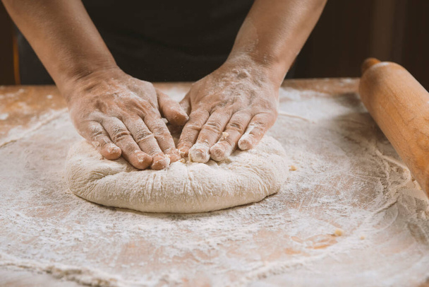 Woman hands kneading dough on a wooden table - Фото, зображення
