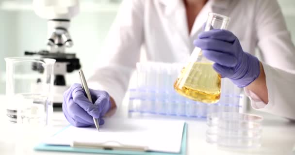 Lo scienziato conduce test di laboratorio di liquido giallo trasparente in fiaschetta. Competenza chimica degli oli cosmetici - Filmati, video