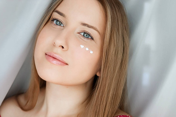 Beautiful woman with skincare cream on her face. - Foto, afbeelding