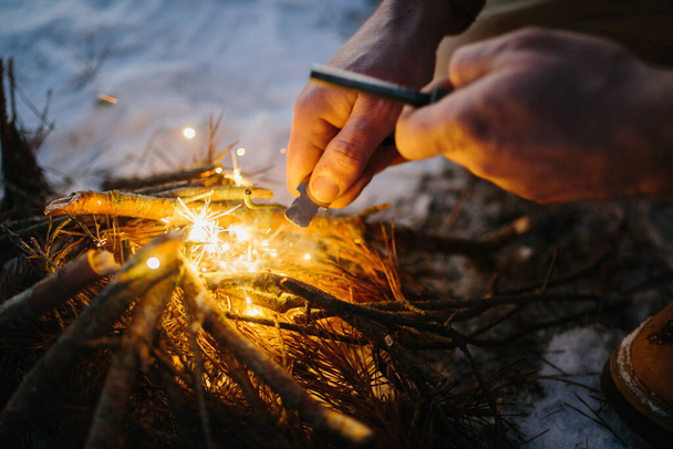 Mano masculina inicia fuego con acero al fuego de magnesio, huelga de fuego - Foto, imagen