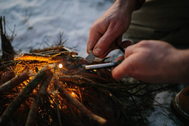 Mannelijke hand start vuur met magnesium vuur staal, brand staking - Foto, afbeelding