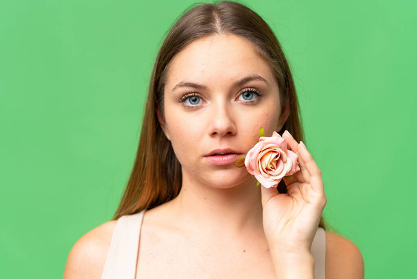 Mujer rubia joven sobre fondo de croma key aislado sosteniendo flores. Primer plano retrato - Foto, imagen