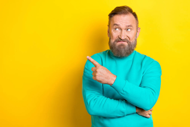 Photo of dissatisfied man wear trendy clothes arm demonstrate empty space bad news information isolated on yellow color background. - Foto, afbeelding