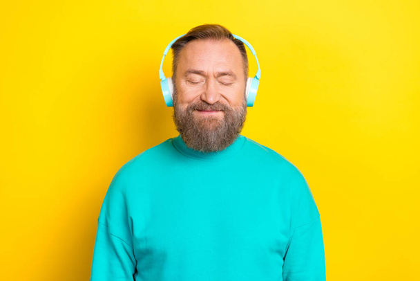 Photo portrait of attractive grandpa closed eyes listen music headphones wear trendy aquamarine garment isolated on yellow color background. - Foto, afbeelding
