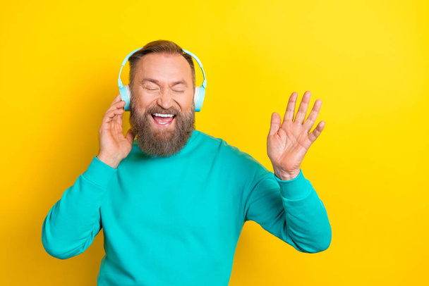 Photo portrait of attractive grandpa listen music enjoy headphones excited dressed stylish cyan look isolated on yellow color background. - 写真・画像